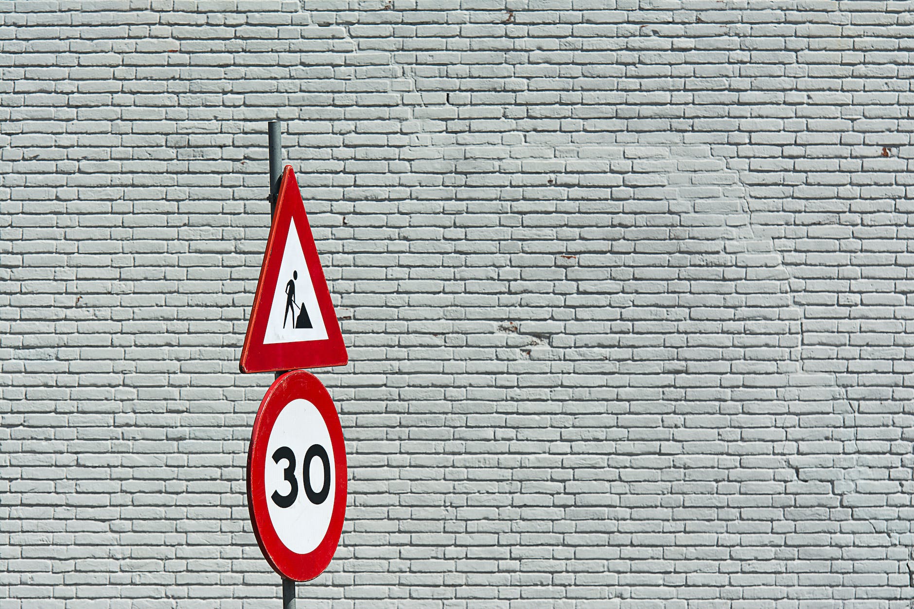 traffic signs against white brick wall